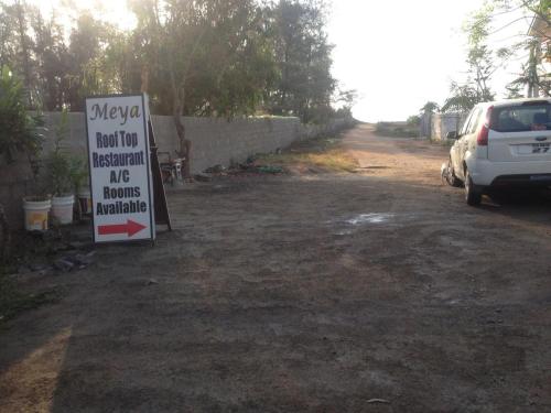 a sign sitting in a parking lot next to a car at Meya Beach Walk Hotel in Mahabalipuram