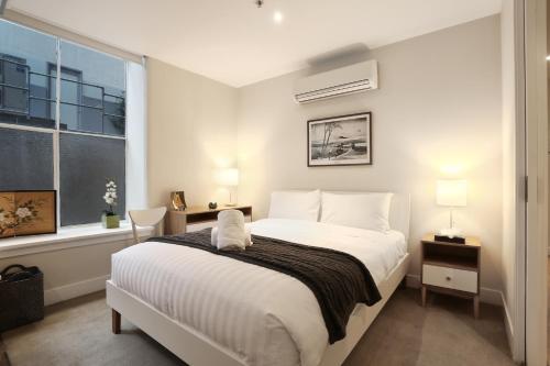 a bedroom with a white bed and a window at StayCentral - Merigold on Collins in Melbourne