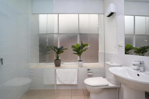 a bathroom with a toilet and a sink and a window at StayCentral - Merigold on Collins in Melbourne