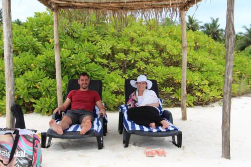 a man and a woman sitting in chairs on the beach at The Castaway retreat in Feridhoo