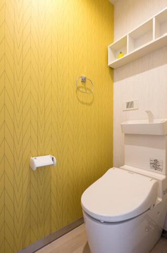 a bathroom with a toilet and a yellow wall at Hotel SAILS in Tokyo