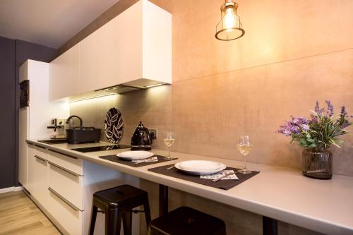 a kitchen with a counter with plates and wine glasses at Jacuzzi Apartments in Kraków