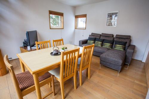 Yotei Cottage في نيسيكو: غرفة معيشة مع طاولة وكراسي وأريكة