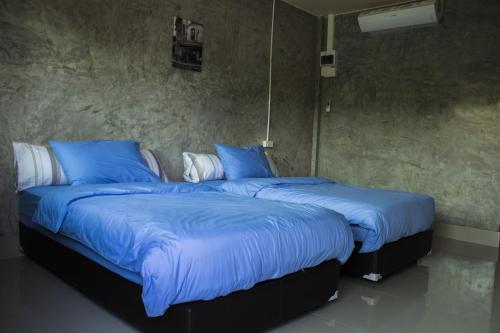 twee bedden in een kamer met blauwe dekens en kussens bij Navy Sisatchanalai in Ban Nong Chang