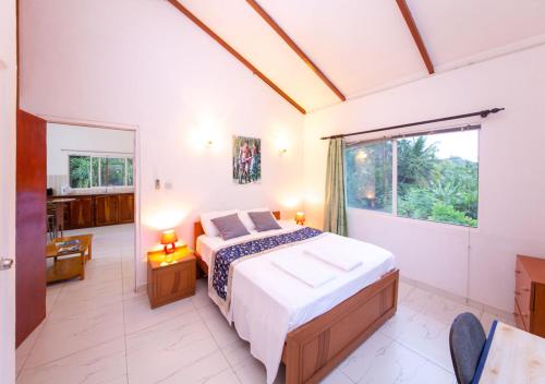 a bedroom with a bed and a large window at Chez Julie in Anse Boileau