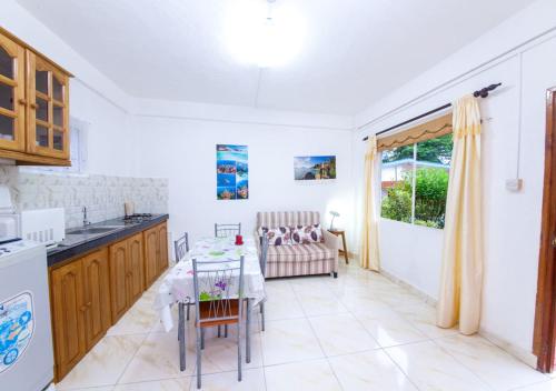 cocina y sala de estar con mesa y fregadero en Chez Julie en Anse Boileau