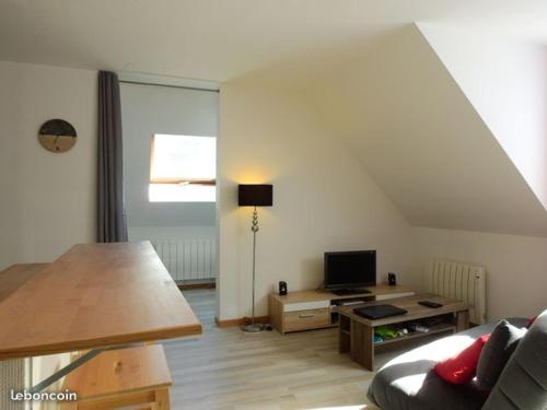 a living room with a couch and a table with a television at Le Saint Antoine in Saint-Jean-de-Maurienne