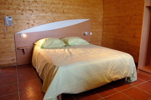 - une chambre avec un grand lit et un mur en bois dans l'établissement Le Clos Boisé, à Théziers