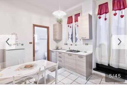 una cucina con tavolo e tavolo e una cucina con tende rosse di Residenza Juvarra Deluxe a Torino