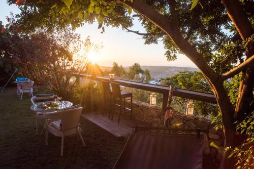 a table and chairs sitting on a deck with the sun setting at Ahuzat Van Gogh in Kefar Weradim