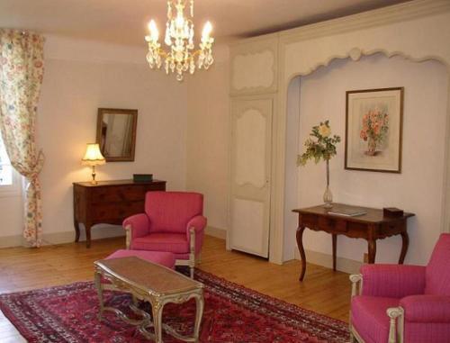 a living room with pink chairs and a table at Appartement du Château du Grand Bouchet in Ballan-Miré