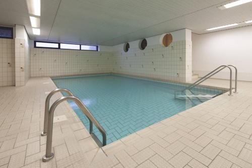 a large swimming pool with blue water in a room at Planke 18 in Norderney