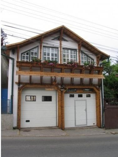 a house with two garage doors and a balcony at Pensiunea Ana Maria in Târgu-Mureş