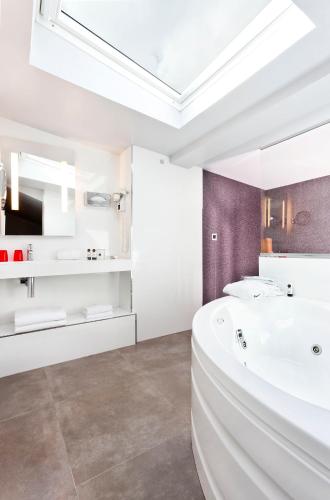 une salle de bain avec une baignoire blanche et un lavabo dans l'établissement Hotel Opéra Marigny, à Paris
