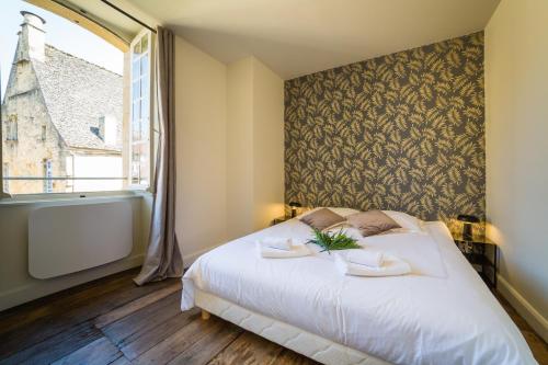 une chambre avec un lit blanc avec une grande fenêtre dans l'établissement Le Grand Appartement d'Albusse, à Sarlat-la-Canéda