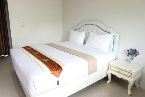 a white bedroom with a white bed and a table at ศุภสิรีวิลล์ in Ubon Ratchathani