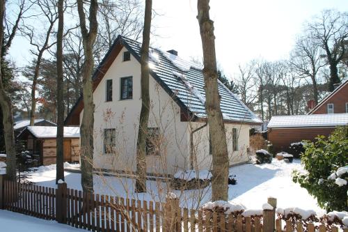 a white house with a fence in the snow at Ferienhaus "Sanddüne No.19" in Boltenhagen