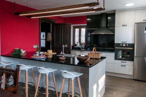 una cocina con paredes rojas y una barra con taburetes en Casa Rural Artola Etxea, en Baráibar