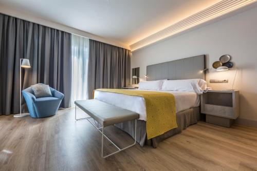 a hotel room with a large bed and a chair at Catalonia Granada in Granada