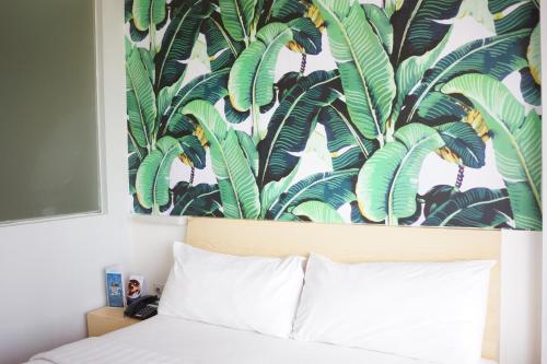 a bedroom with a bed with a tropical wallpaper at Liberta Hotel Kemang in Jakarta
