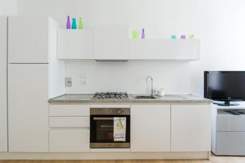 a white kitchen with a stove and a microwave at Belvedere White Flat in Trieste