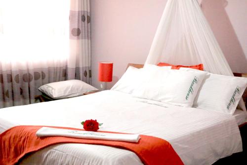 a bedroom with a large white bed with a red flower on it at Bankhouse Retreat Karen in Nairobi