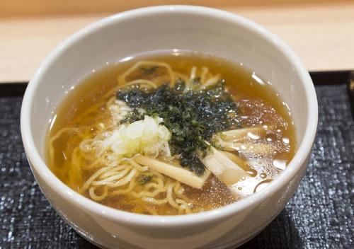 a bowl of soup with noodles and greens in it at Dormy Inn Korakuen in Tokyo