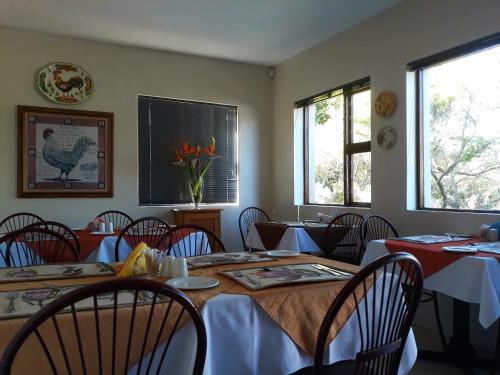 a dining room with tables and chairs and two windows at Albert Road Garden Guest House in Port Elizabeth