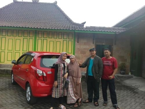 a group of people standing next to a red car at Pendopo Kayuwanan Syariah Near Terminal Giwangan in Yogyakarta