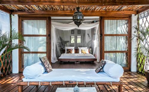 a porch with a bed in a room with windows at Baia Sonambula in Praia do Tofo