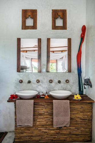 a bathroom with two sinks and a mirror at Baia Sonambula in Praia do Tofo