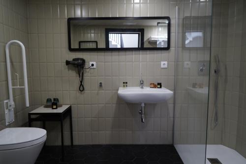 a bathroom with a sink and a toilet and a mirror at MD Design Hotel - Portal del Real in Valencia