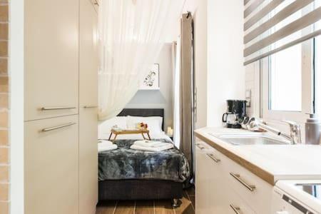 a white kitchen with a bed and a sink at Cozy studio 50m from sea in Athens