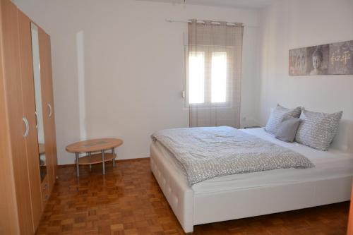 a white bedroom with a bed and a table at Taris in Senj