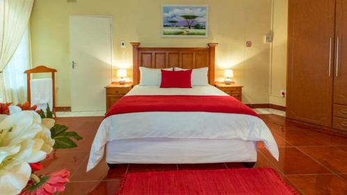 a bedroom with a large bed with a red blanket at Gannet Place Guest House in Hazyview