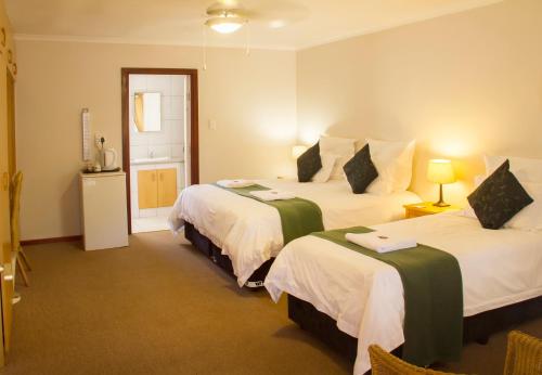 a hotel room with two beds and a television at Albert Road Garden Guest House in Port Elizabeth