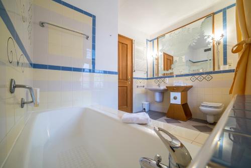 a bathroom with a tub and a toilet and a sink at Aparthotel Tři lilie in Františkovy Lázně