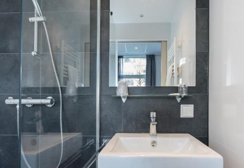 uma casa de banho com um lavatório e um chuveiro em City2Beach Hotel em Vlissingen