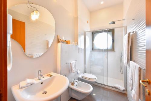 a bathroom with a sink and a toilet and a mirror at Hotel d'Altavilla in Canosa di Puglia