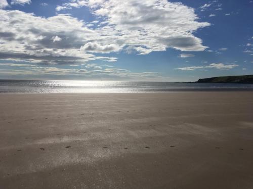 a sandy beach with a cloudy sky and the ocean at Balnabrechan Lodge in Arbroath
