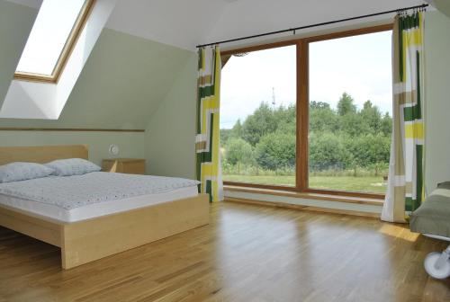 ein Schlafzimmer mit einem Bett und einem großen Fenster in der Unterkunft Vilks un Briedis Holiday Home & Wellness Area in Smiltene