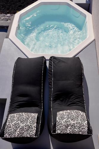 a pair of black and white chairs next to a pool at Elysian Santorini in Oia