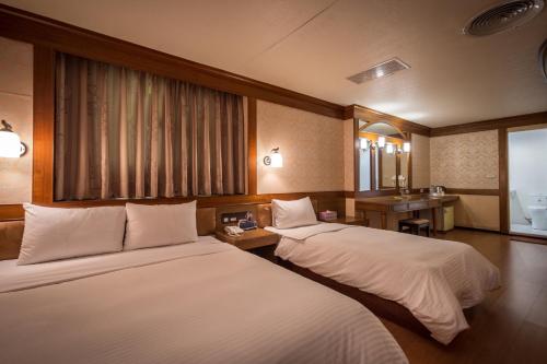 a hotel room with two beds and a sink at Golden Phoenix Hotel in Kaohsiung
