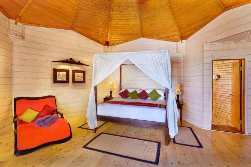 a bedroom with a bed and a chair in a room at Komandoo Island Resort & Spa in Komandoo