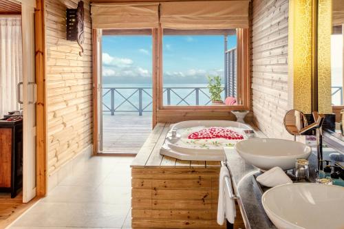 a bathroom with a tub with a view of the ocean at Komandoo Island Resort & Spa in Komandoo