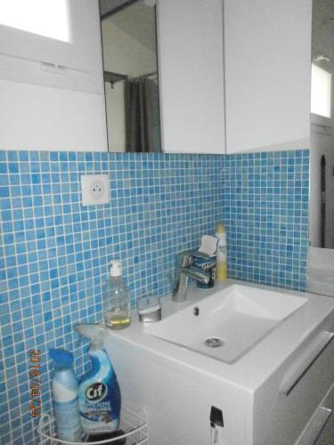 La salle de bains est pourvue d'un lavabo et d'un mur carrelé bleu. dans l'établissement Studio équipé avec jardin+parking à la plage..., à La Ciotat