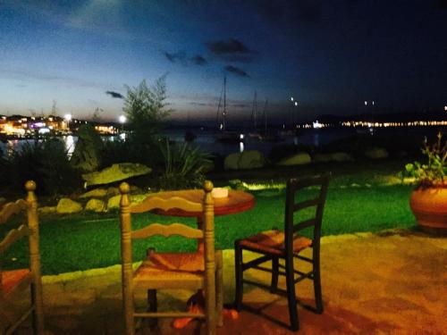 two chairs and a table on a patio at night at Case sul mare in Palau