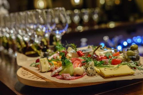 a plate of food on a table with wine glasses at Hotel Tigra in Priekuļi