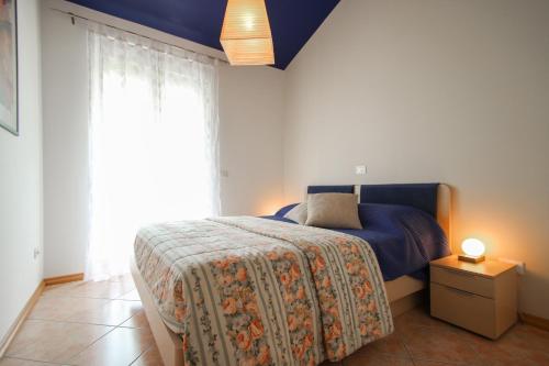 een slaapkamer met een bed met een blauwe deken en een raam bij Denis in Novigrad Istria