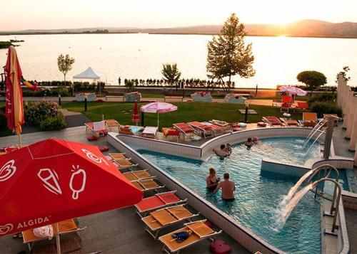 a pool with chairs and people in a resort at Velence Spa Lake Apartman in Velence